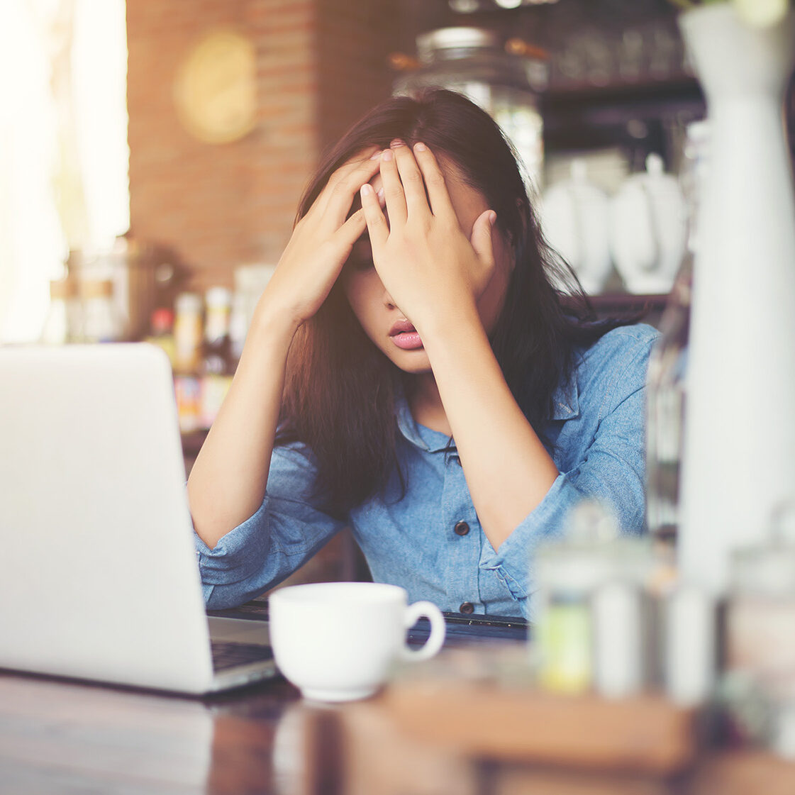 Young woman sitting in a cafe with her laptop, Stressful for work.